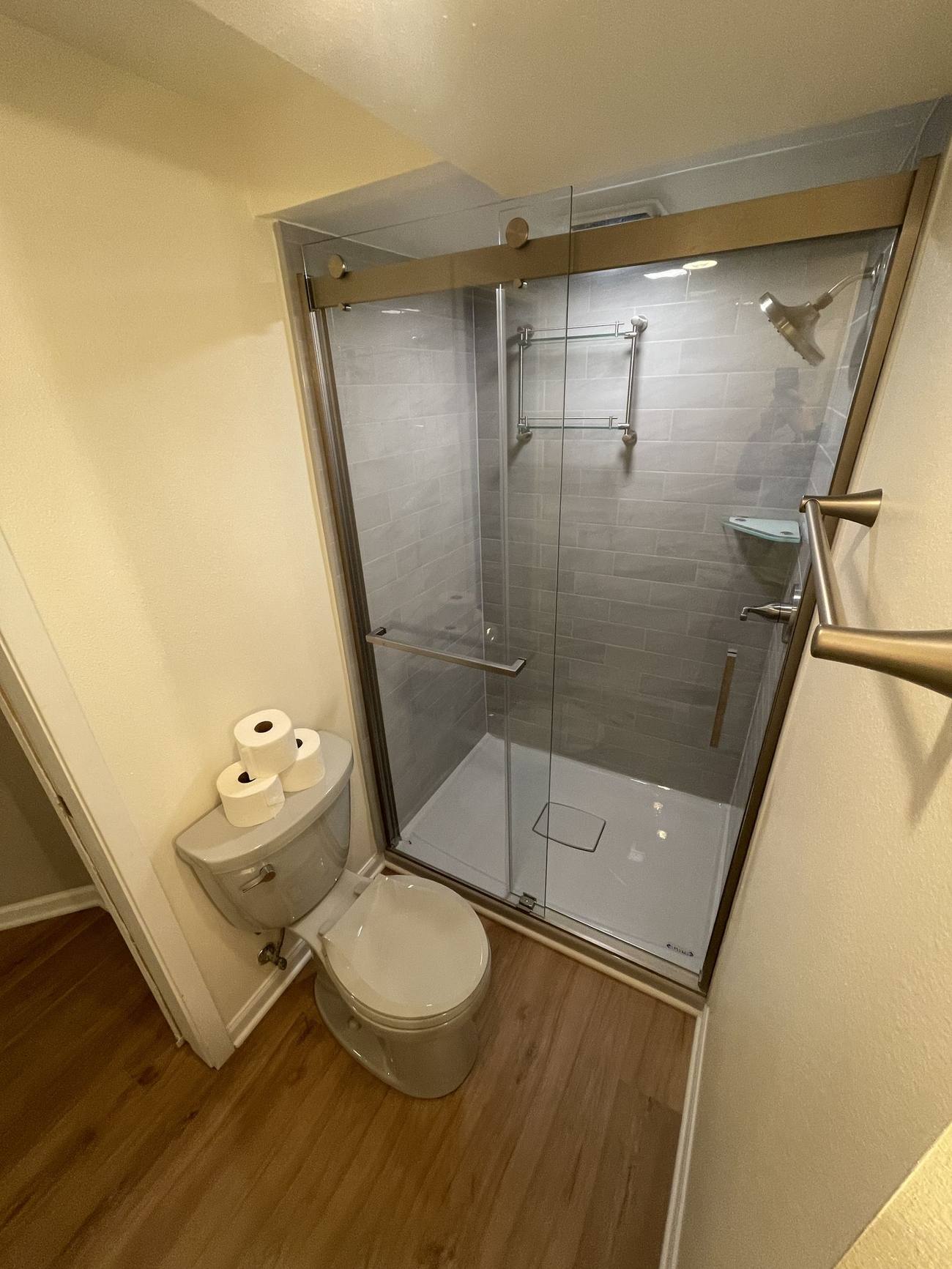 Remodeled basement shower with gray subway tile and frameless glass sliding door by Ask Adam, Madison WI